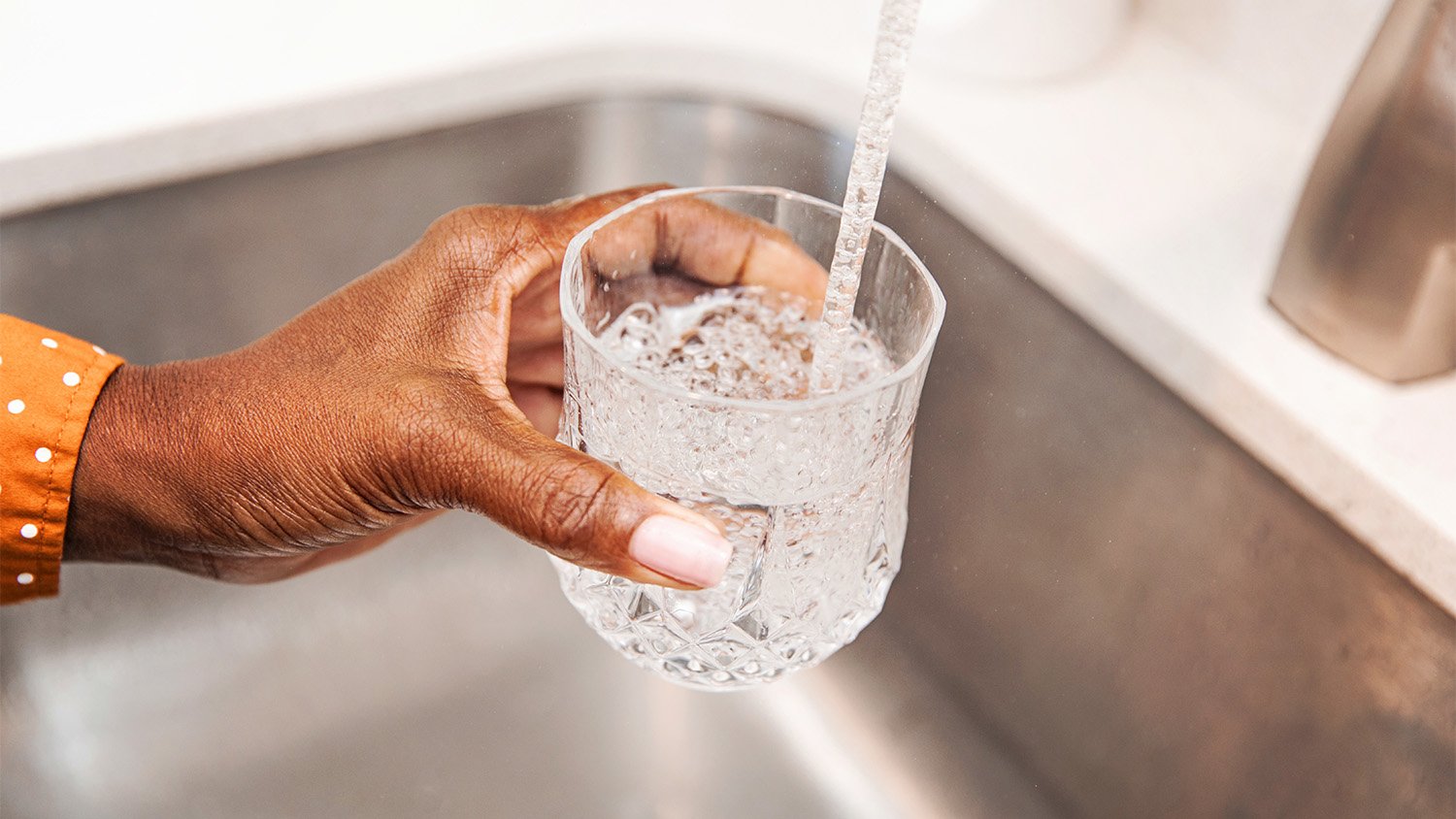 woman getting tap water into glass